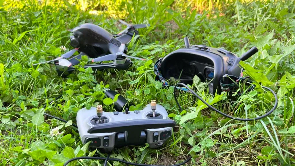 dji fpv drone, dji fpv remote controller 2 and dji fpv goggles v2 on grass outdoors